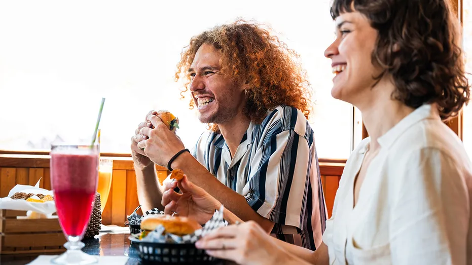 man-and-woman-laugh-while-eating-burger