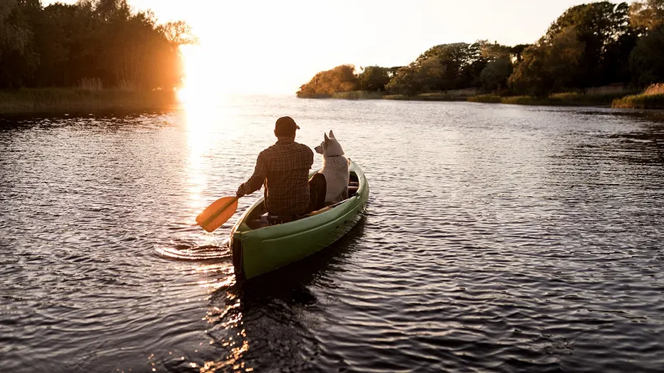 man-dog-canoeing-river-sunset