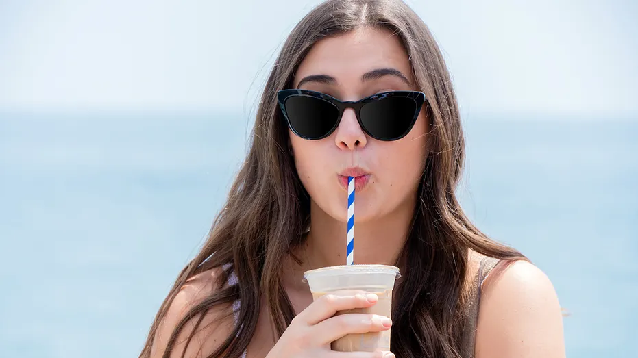 woman-drinking-iced-coffee-on-beach